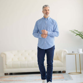 Man in a blue and white grid long sleeve button-down shirt with magnetic closures, standing in a bright living space.