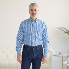 Man wearing a blue and white checked long sleeve button-down shirt with magnetic closures, smiling indoors.