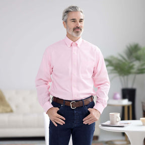 Man in pink long sleeve button-down collar shirt with magnetic closures, standing in a modern living space.