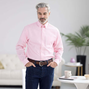 Man wearing a pink long sleeve button-down collar shirt, featuring magnetic closures, in a bright living room.